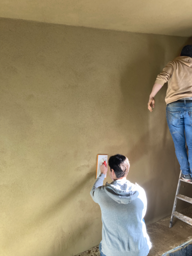 Lehmputz-Auftrag Handwerker trägt glatten Lehmputz auf rohe Wand auf – nachhaltig, atmungsaktiv und warm.